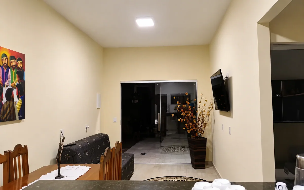 Sala de estar e jantar com sofa estampado, mesa de madeira e TV na parede