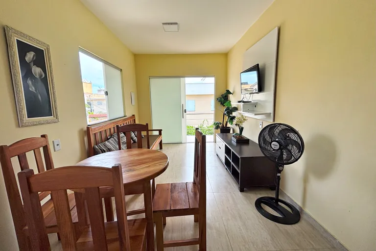 Sala integrada com mesa de jantar de madeira TV e janela com luz natural