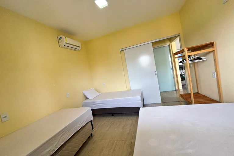 Quarto com cama de casal e solteiro ar condicionado e passagem para o closet