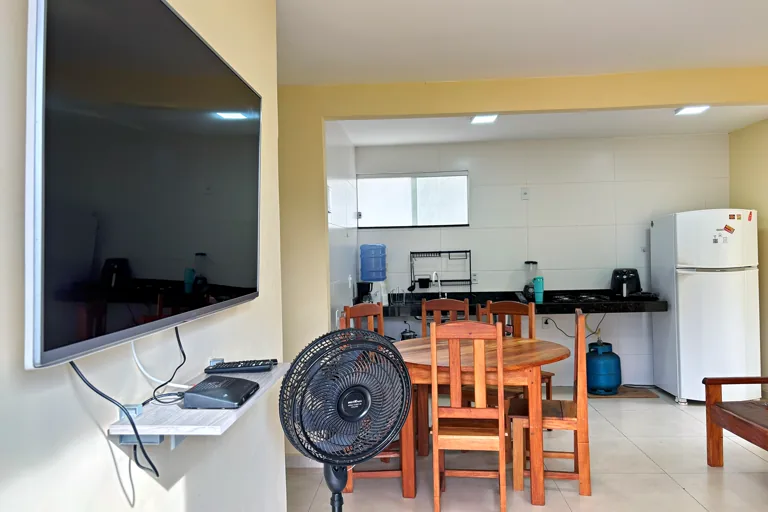 Sala com Smart TV mesa de jantar e cozinha ao fundo