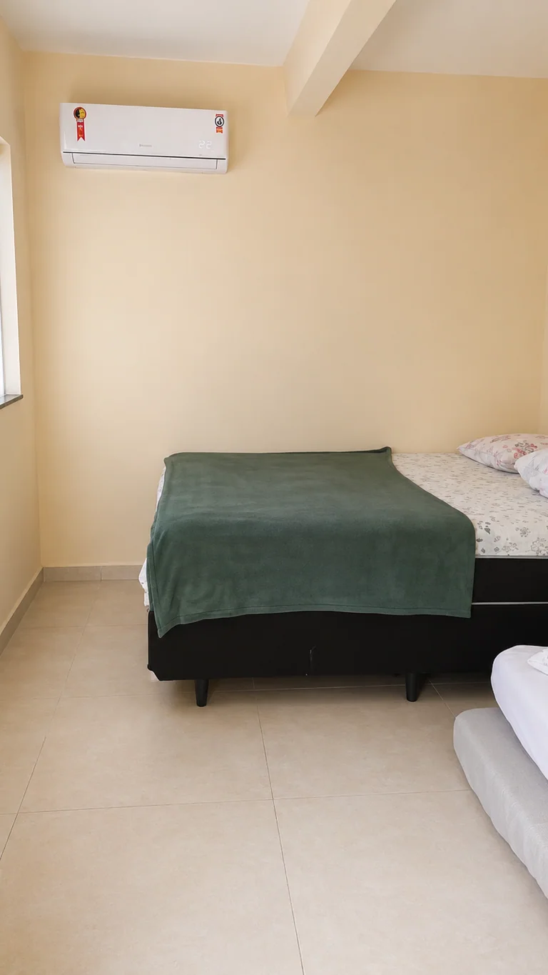Quarto com camas de solteiro, cama de casal parcialmente visivel e ar-condicionado