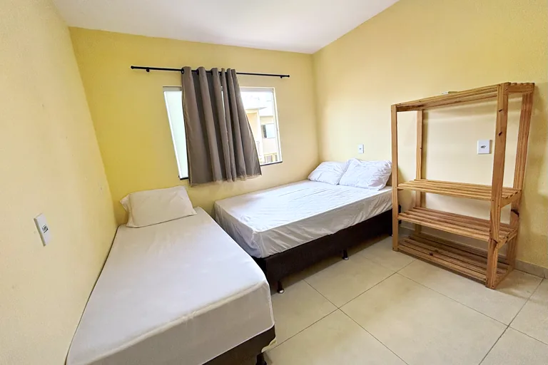 Quarto com cama de casal e cama de solteiro estante de madeira e janela