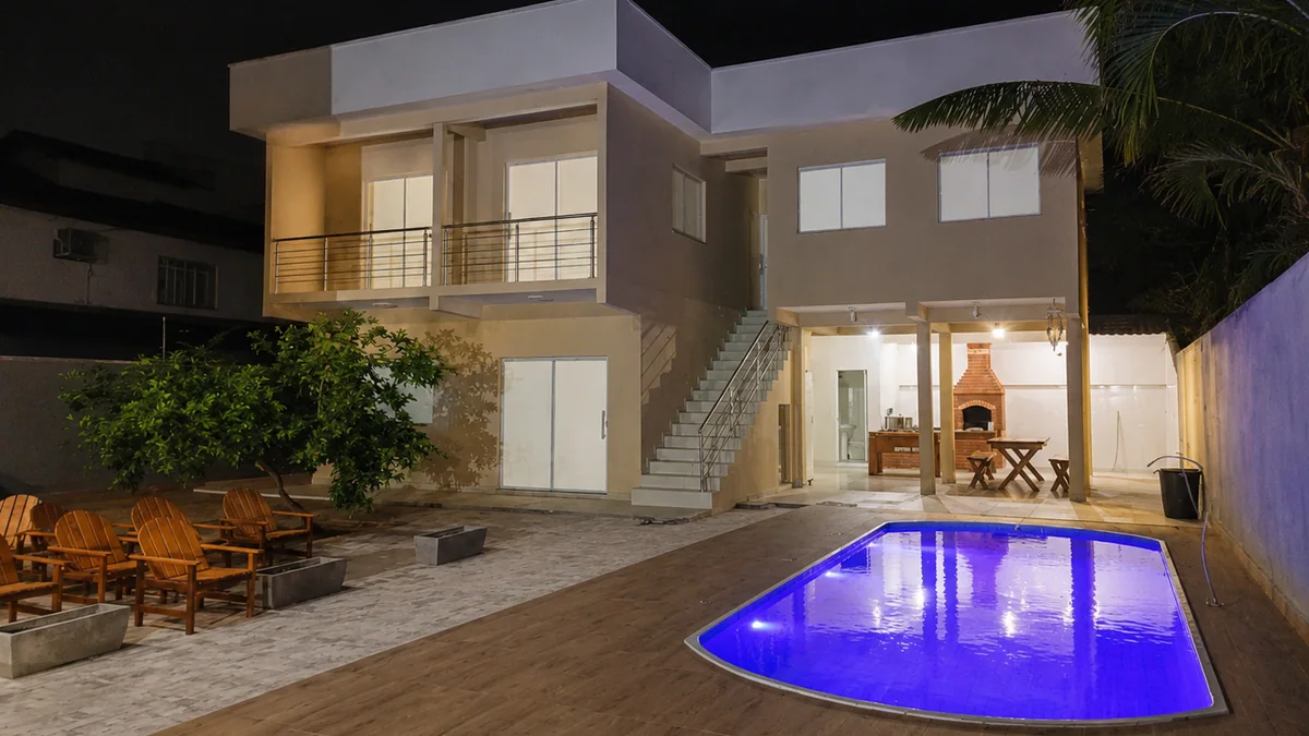 Sobrado do residencial a noite, com a piscina compartilhada iluminada e a area de convivio com churrasqueira