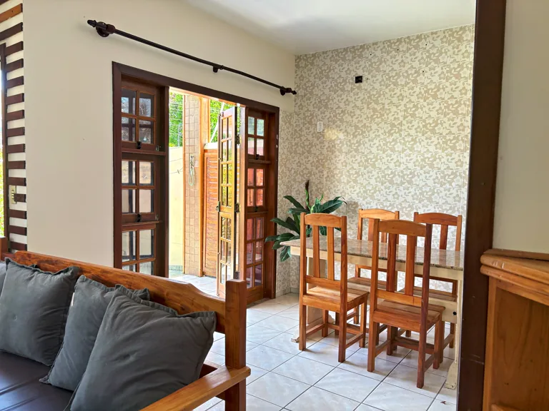 Sala integrada da Casa Naira com sofa e acesso ao patio