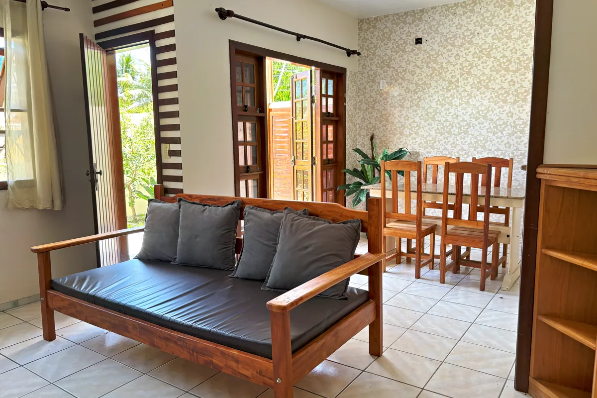 Sala de estar e jantar integradas com sofá de madeira e mesa para seis
