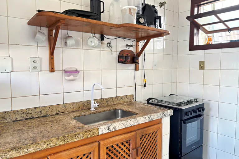 Cozinha com pia de granito fogao quatro bocas e janela com luz natural