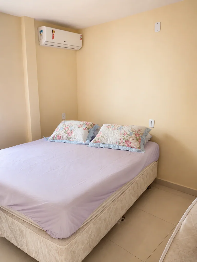 Quarto com cama de casal, ar-condicionado e roupa de cama clara