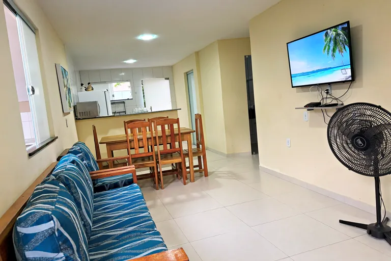 Sala de estar com sofa, mesa de jantar e cozinha americana ao fundo