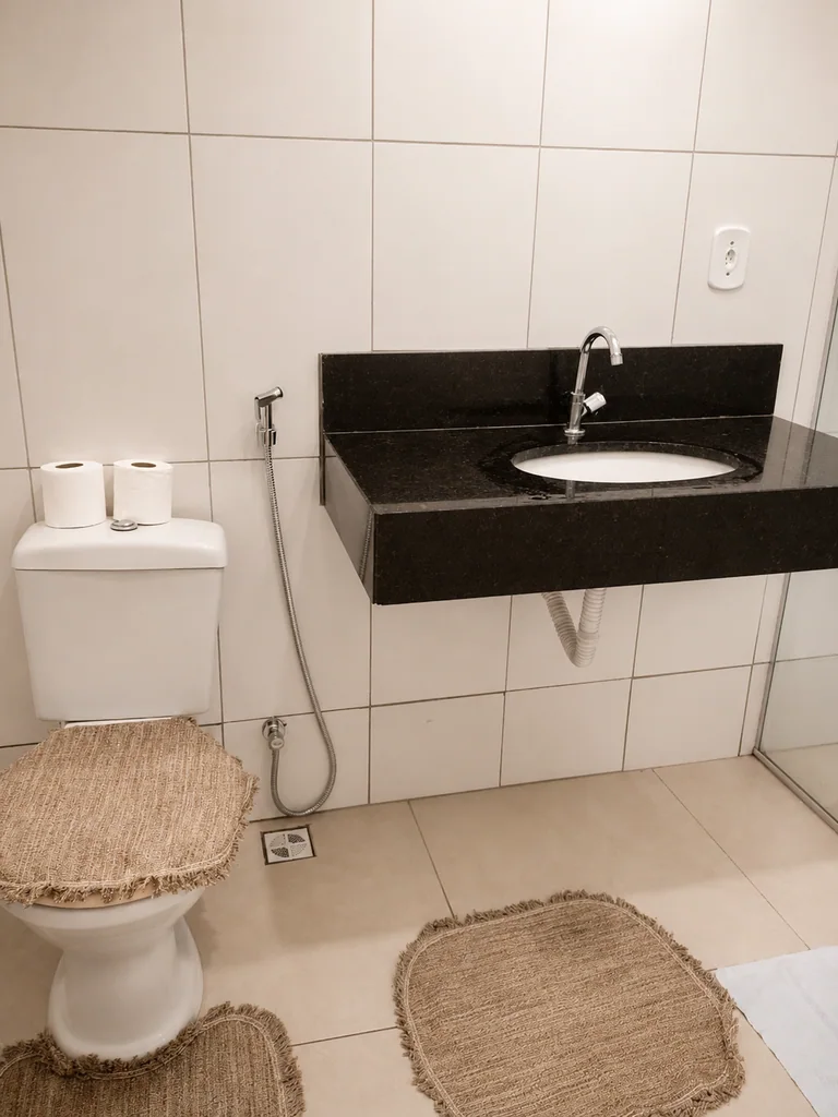Banheiro com vaso sanitario, pia com bancada preta e box de vidro