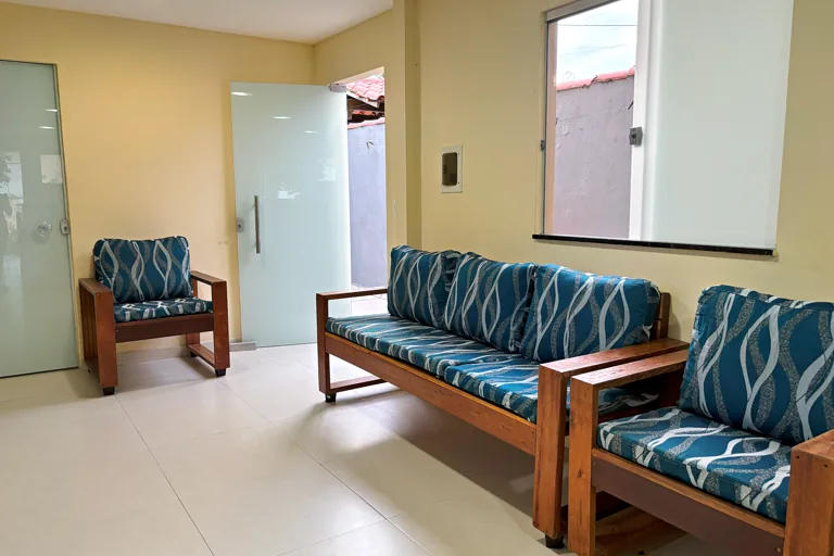 Sala de estar com sofa e poltronas de madeira e acesso externo