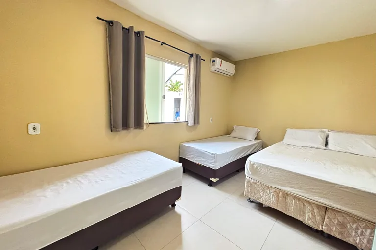 Quarto com cama de casal e duas de solteiro com janela e ar-condicionado