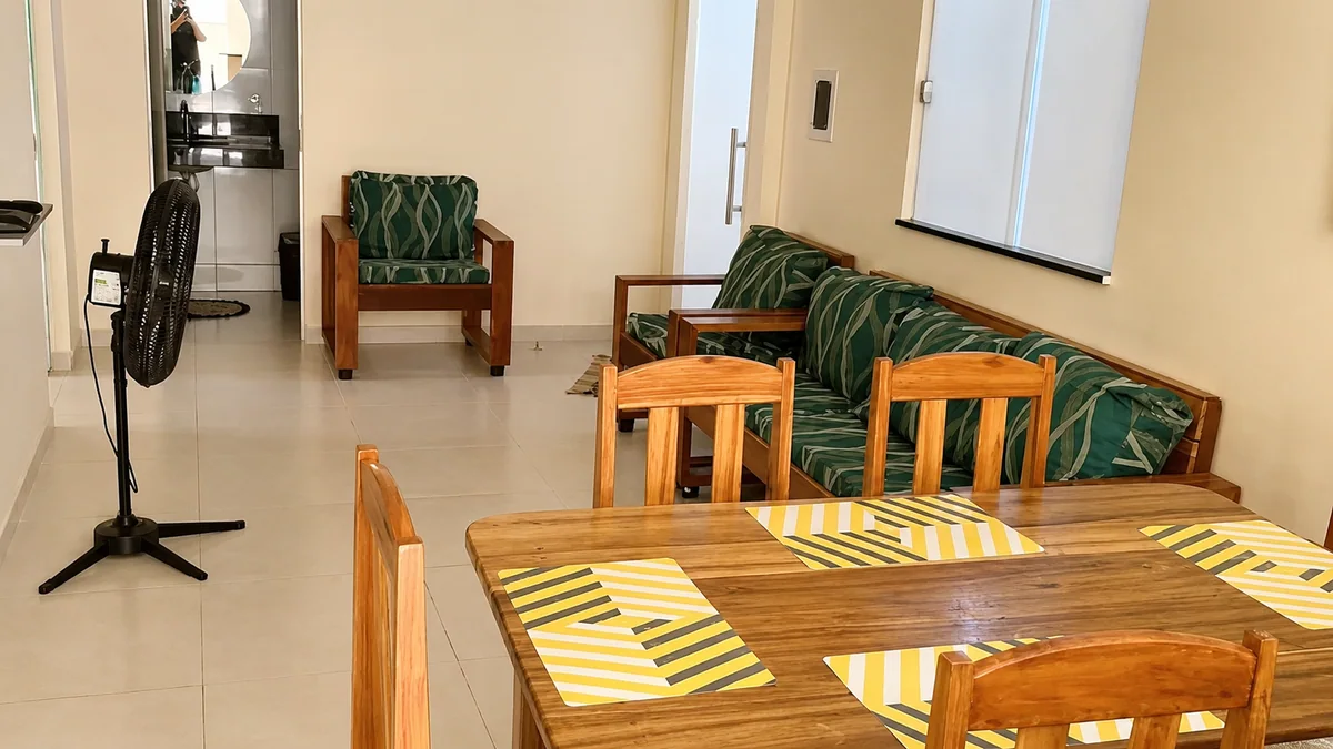 Sala e jantar da Casa Pitanga com mesa de madeira, sofa, poltrona e ventilador